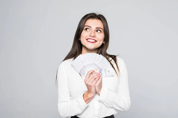 Портрет усміхненої молодої жінки, що тримає готівкові долари, стоячи на білому — стокове фото