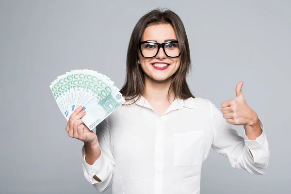 Portrét veselá dívka pokrývající její oko s euro bankovky a ukazuje palcem izolované na bílém pozadí — Stock fotografie
