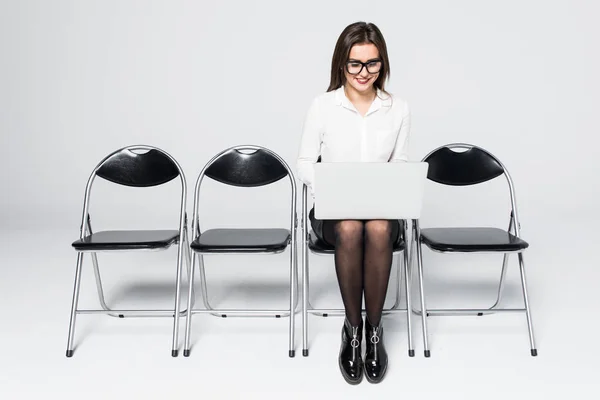 Jeune travailleuse de bureau souriante assise sur une chaise de plancher en bois à l'aide d'un ordinateur portable mobile préparer un dossier de réunion d'entrevue isolé sur blanc — Photo