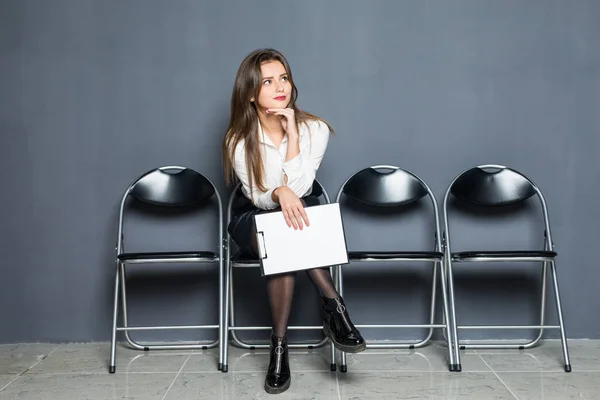 Ritratto di giovane donna seria e sicura di sé seduta sulla sedia in sala d'attesa con vuoto, che si mette in testa prima di un colloquio di lavoro o di un incontro con potenziali partner commerciali — Foto Stock