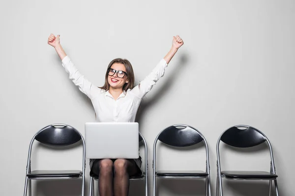 Young smiling office worker woman sitting on wood floor chair using mobile laptop computer with raised hands before prepare interview meeting file in office hall — Stock Photo, Image