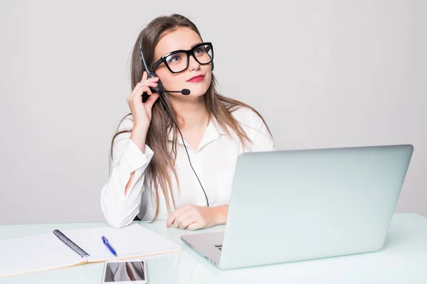 Retrato de una hermosa mujer de negocios trabajando en su escritorio con auriculares y portátil — Foto de Stock