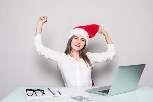 Jovem mulher bonita vestindo um chapéu de Natal com as mãos levantadas trabalhando no escritório — Fotografia de Stock