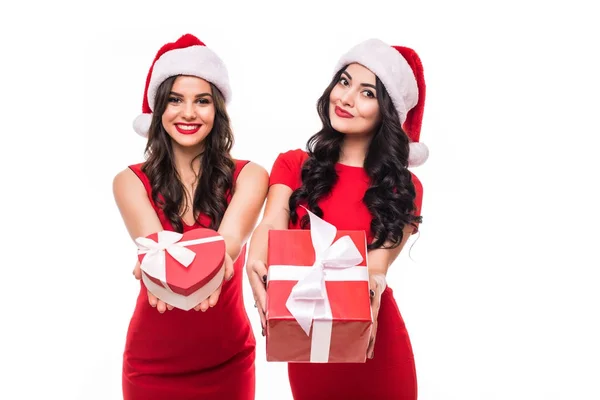 Retrato de alegres mujeres felices en sombreros de Navidad sosteniendo cajas presentes mientras están de pie y mirando cámara aislada sobre fondo blanco —  Fotos de Stock