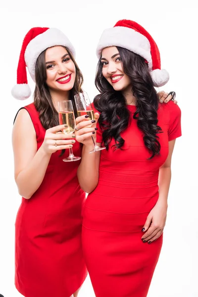 Kırmızı elbiseler ise toasting ve beyaz arka plan üzerinde izole kamera bakarak şampanya ile gözlük tutan iki mutlu gülümseyen kız portresi