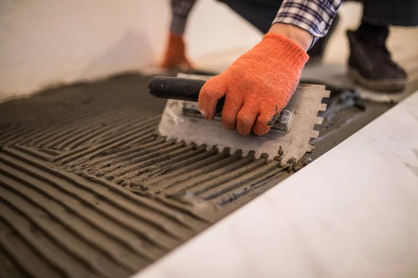 Laying Ceramic Tiles. Troweling mortar onto a concrete floor in preparation for laying white floor tile. — Stock Photo, Image