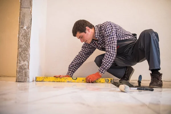 Home tile improvement handyman with level laying down tile floor