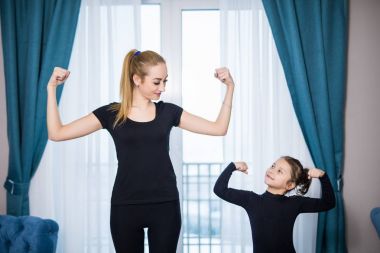 Güzel genç kadın ve sevimli küçük kızını onların pazı gösterilen ve evde dışarı çalışırken gülümseyen