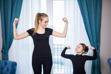 Güzel genç kadın ve sevimli küçük kızını onların pazı gösterilen ve evde dışarı çalışırken gülümseyen