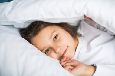 Sevimli küçük kız yatakta evde battaniyenin altında yalan pijama