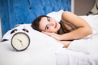 Uyuyan kadın ve çalar saat evde yatak odasında genç gülümsemek