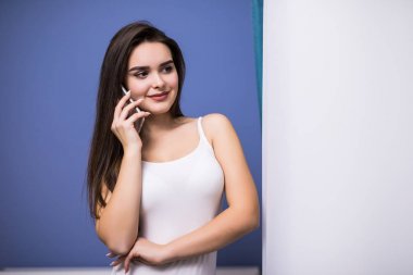 Perdeler pencere tarafından cep telefonu kullanan mutlu genç kadın,