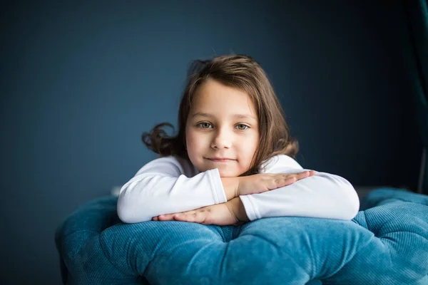Kis fiatal gyerek ül a székre kezek, arc szépség mosoly pillantást a kamera szobájába otthon — Stock Fotó