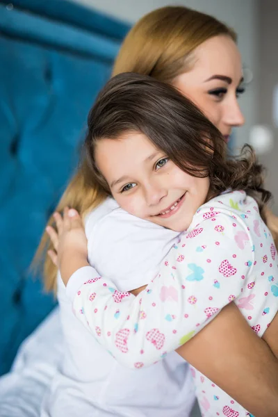 美丽的年轻女子和她迷人的小女儿在家里的床上拥抱和微笑 — 图库照片
