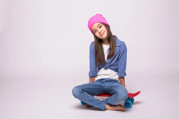 Boldog kis lány rose kalap gördeszkás ül a longboard, elszigetelt fehér background — Stock Fotó