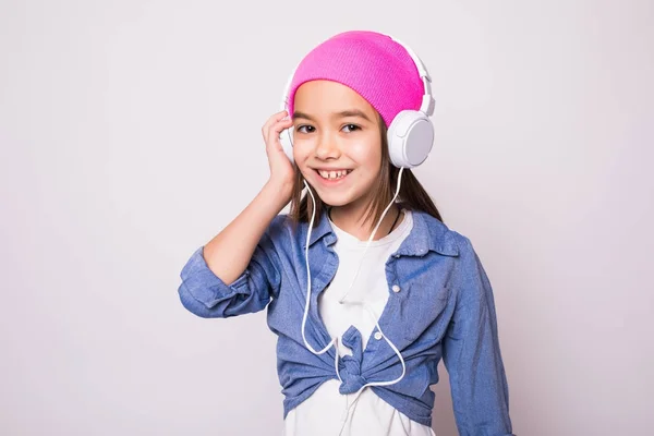 Chica sonriente con auriculares escuchando música aislada en blanco — Foto de Stock