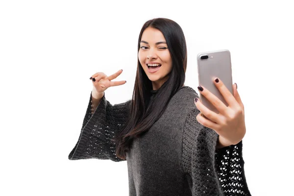 Alegre joven mujer de pie aislado sobre fondo blanco hacer un selfie con gesto de paz — Foto de Stock