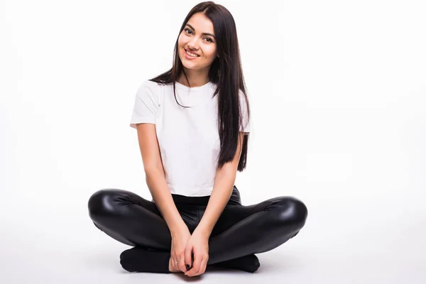 Fiatal nő ül a földön, és mosolygott, fehér háttér — Stock Fotó