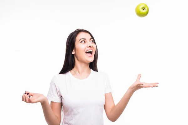 Portrait of a smiling happy girl throwing apple in the air over white background — Stock Photo, Image