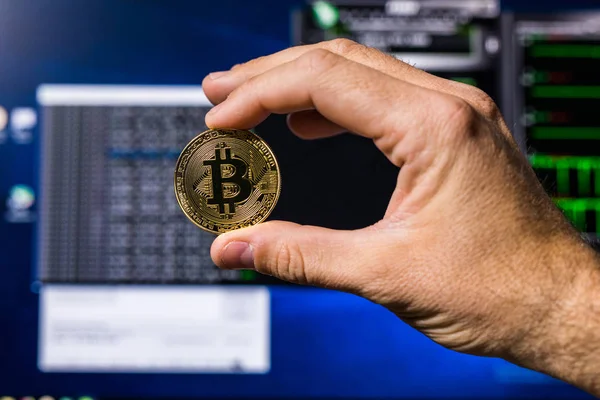 Un bitcoin de oro en la mano de una mujer en un fondo brillante de los gráficos de negocios de cerca. Bitcoin-Crypto moneda . — Foto de Stock