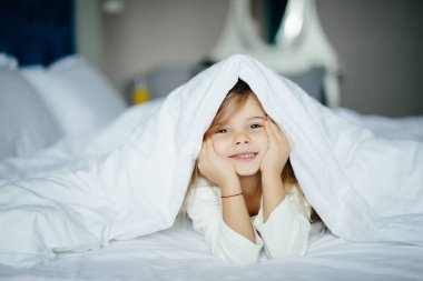 Sevimli küçük kız evde battaniyenin altında yalan pijama