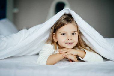 Sevimli küçük kız evde battaniyenin altında yalan pijama