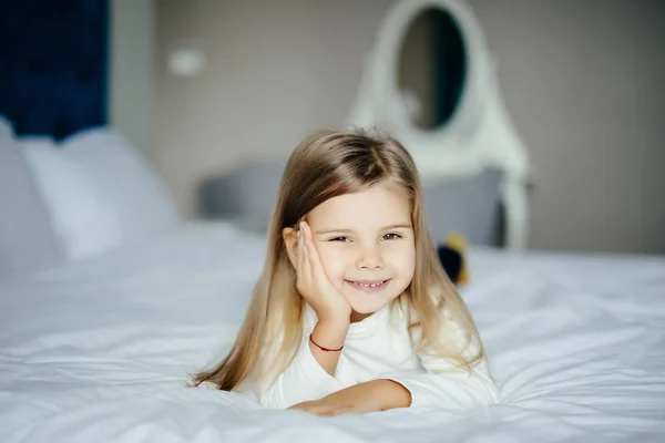 Милая маленькая девочка лежит в постели дома в спальне — стоковое фото