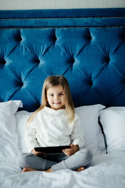 Милая девушка с планшетным компьютером в своей спальне дома — стоковое фото