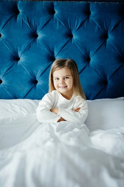 Маленькая девочка, сидящая в постели с копирайтом — стоковое фото