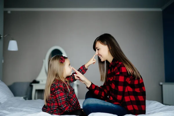 幸福的爱的家庭。母亲和她的女儿女孩在床上玩耍和抚摸对方的鼻子. — 图库照片