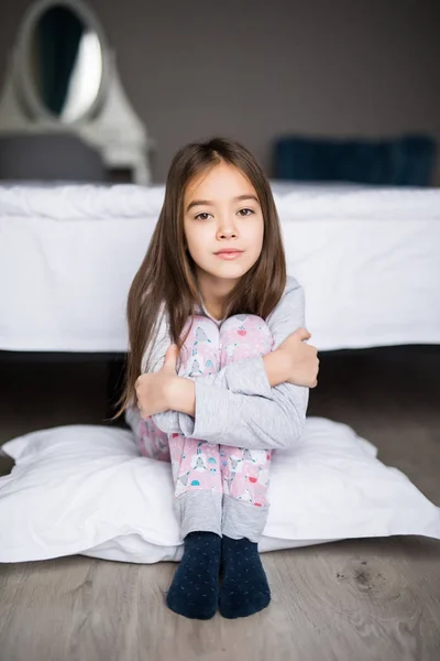 Портрет расстроенной депрессии маленькой девочки, сидящей на полу возле кровати утром — стоковое фото