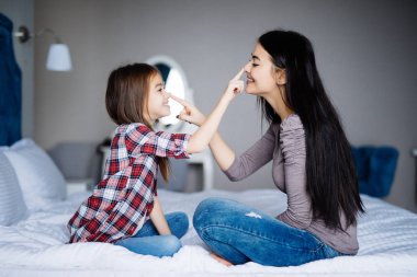 Anne ve kızı evde yatak burnuna dokunuyor