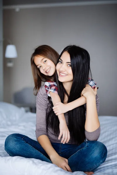 快乐的女孩在家拥抱她的母亲在床 — 图库照片