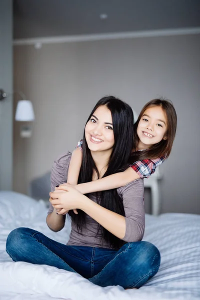 在床上闭上年轻女孩拥抱年长的妹妹的画像。姐妹在床上拥抱. — 图库照片