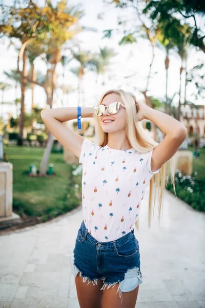 Mulher usando óculos de sol posando com palmeira na rua — Fotografia de Stock