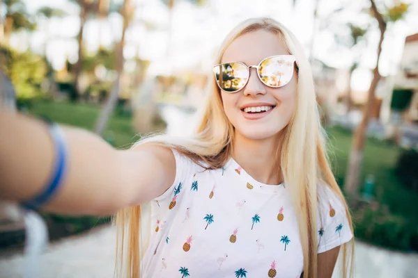 여름 리조트 손바닥 배경에 휴대폰 selfie을 복용 하는 선글라스에 쾌활 한 젊은 여자. 여름 직업 — 스톡 사진
