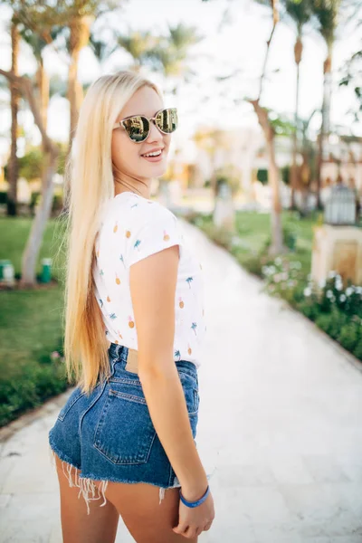 Sorrindo bonito jovem mulher de chapéu andando em resort de verão — Fotografia de Stock