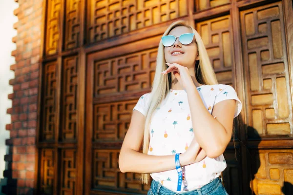 Primer plano retrato de una joven hermosa mujer rubia en gafas de sol posando afuera con pared de madera en el fondo. Estilo calle verano primavera foto —  Fotos de Stock