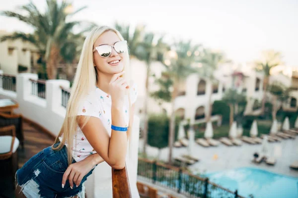 Ritratto di bellezza estate ragazza in occhiali da sole sul balcone della camera d'albergo guardare palme giardino sullo sfondo — Foto Stock