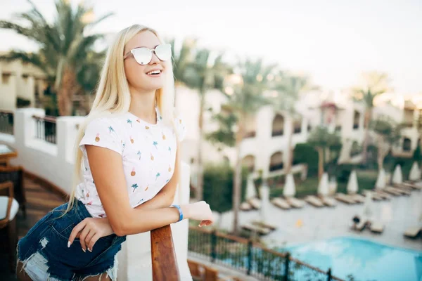 Retrato de beleza menina de verão em óculos de sol na varanda do quarto de hotel olhar para palmas jardim no fundo — Fotografia de Stock