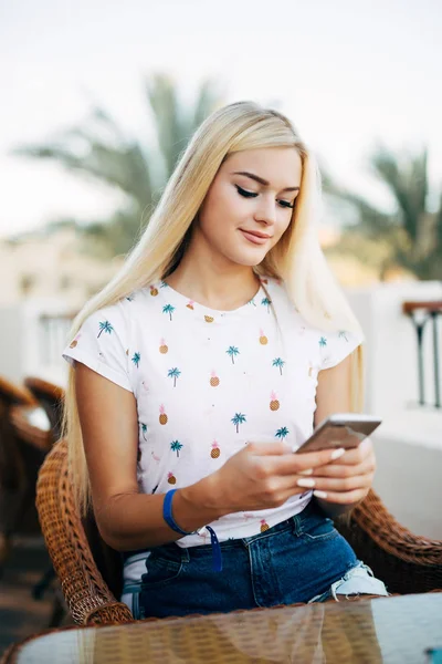 Koncentrerad ung kvinna att skriva ett textmeddelande på hennes mobiltelefon utomhus. Leende kvinna med smartphone. — Stockfoto
