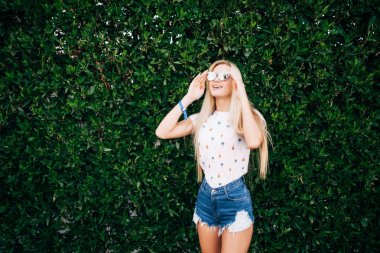 Meslek ayakta duvar arka plan yaprakları yaz güneş gözlüklü güzel sarışın kadın