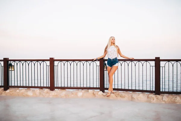 Linda chica feliz disfruta de vacaciones de verano en el complejo. Retrato de la joven alegre en camisa blanca de pie en la terraza sobre fondo de mar increíble —  Fotos de Stock