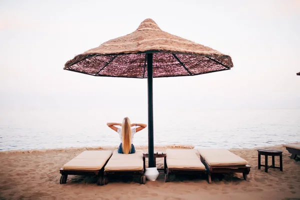 Mujer en la playa sur descansando en una chaise-longue bajo un paraguas. Viaje de verano. Vibraciones de playa — Foto de Stock