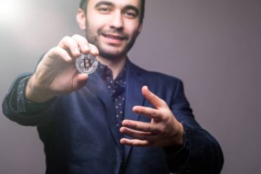 Handome iş adamı işaret etti, yakın bitcoin tonned ışık ile karanlık arka plan üzerinde izole kamera