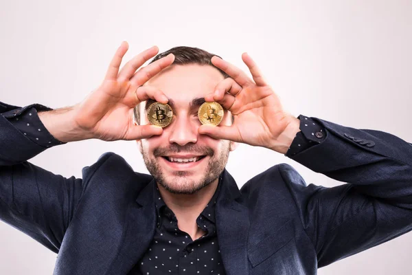 Jovem bonito homem cobrir os olhos com bitcoin moedas isoladas no fundo cinza — Fotografia de Stock
