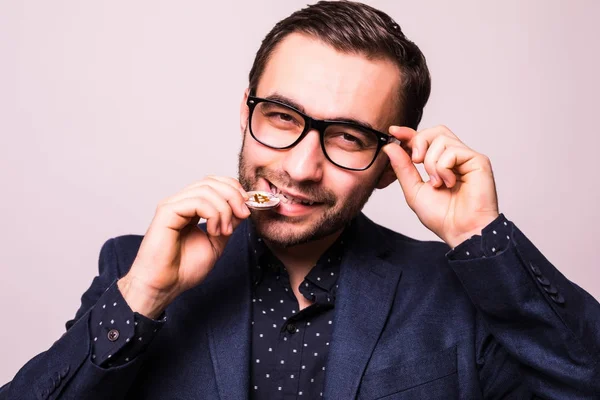 Genç yakışıklı iş adamı gözlük ısırık bitcoin cion gri arka plan üzerinde izole içinde — Stok fotoğraf