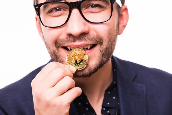 Retrato de un joven hombre de negocios muerde Bitcoin aislado sobre fondo blanco. El hombre muerde una moneda de oro con sus dientes —  Fotos de Stock