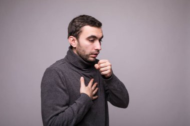 Genç adam gri arka plan üzerinde öksürük