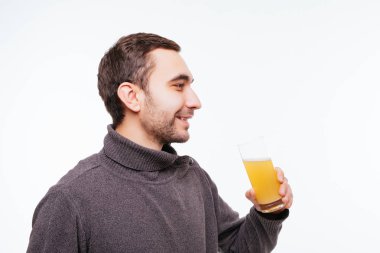 Yakışıklı adam gri arka plan üzerine portakal suyu içiyor